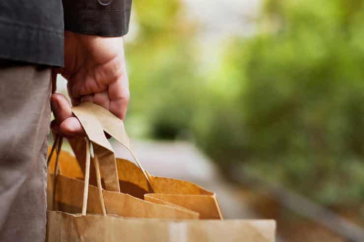 consumer basket, close up of paper shopping bags in male hand